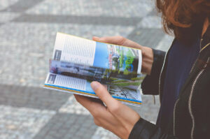 © Bild Urlaubsplanung by https://www.pexels.com/de-de/foto/frau-im-schwarzen-reissverschlussjacke-hoding-white-and-blue-book-122162/